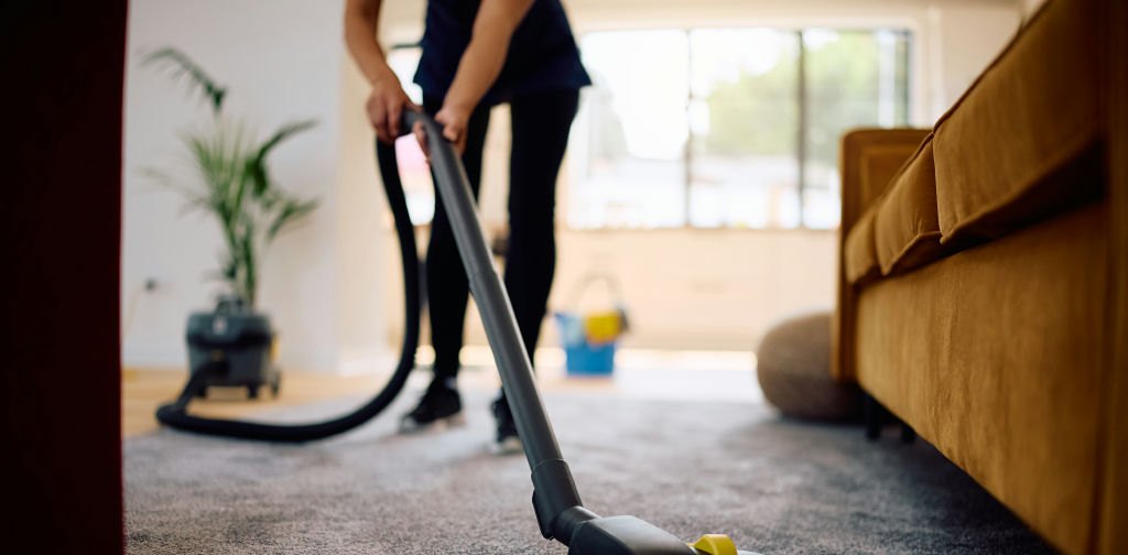 Sash & Co. cleaner vacuuming a living room carpet